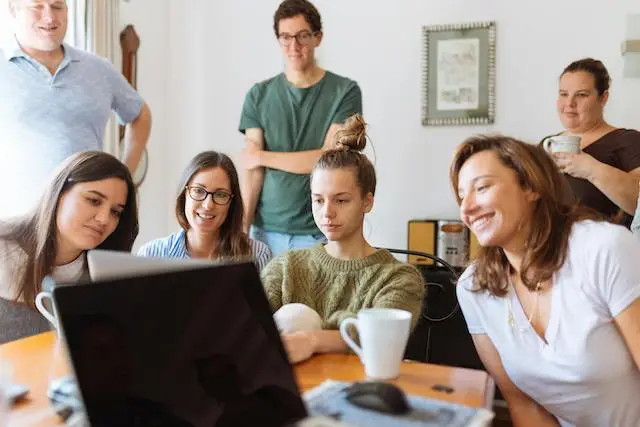 Young adults gathered around a laptop engaged in AI skills training.